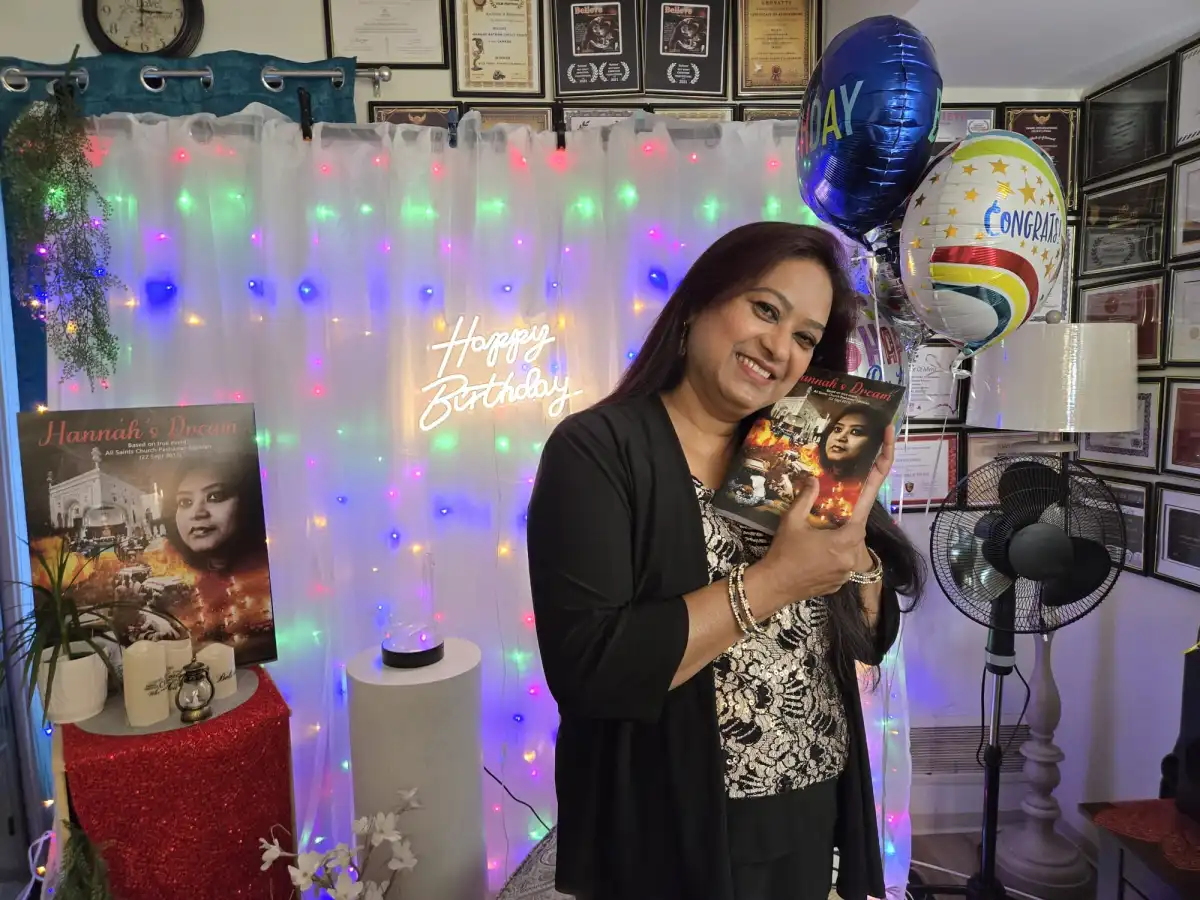 Hannah Ratnam holding a copy of her work in a celebratory portrait